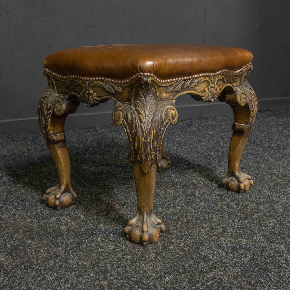 A low Chippendale style stool featuring a brown leather upholstered seat with brass stud detailing and dark carved cabriole legs ending in claw and ball feet. View VI