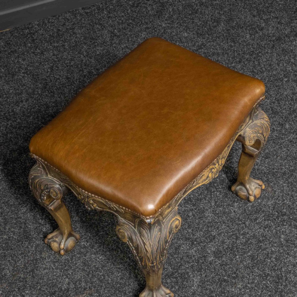 A low Chippendale style stool featuring a brown leather upholstered seat with brass stud detailing and dark carved cabriole legs ending in claw and ball feet. View VII