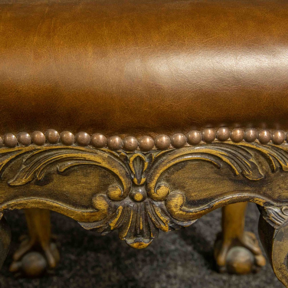 A low Chippendale style stool featuring a brown leather upholstered seat with brass stud detailing and dark carved cabriole legs ending in claw and ball feet. View VIII