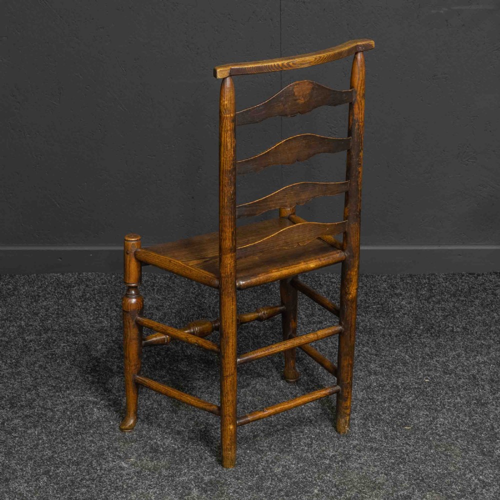 A set of eight Georgian oak dining chairs featuring wavy ladderbacks, solid panel seats, and turned front stretchers. View V