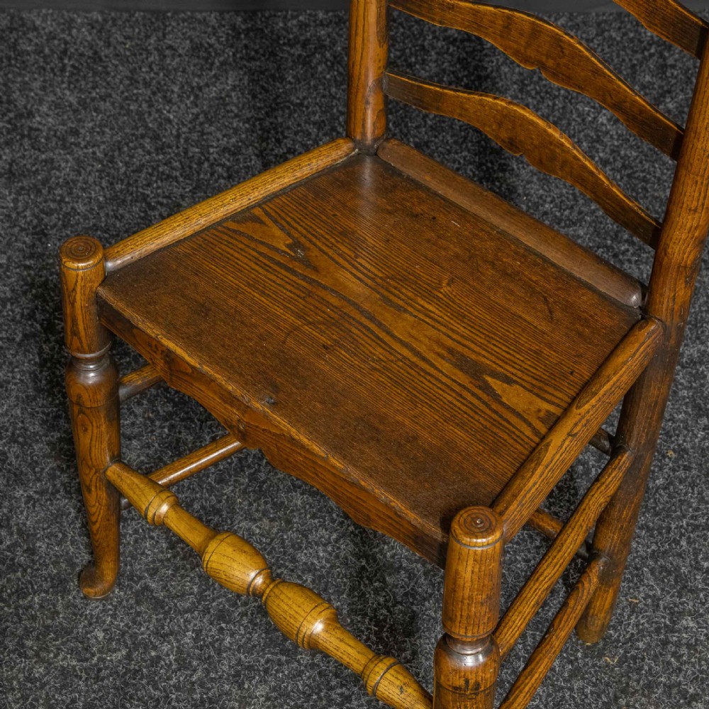 A set of eight Georgian oak dining chairs featuring wavy ladderbacks, solid panel seats, and turned front stretchers. View VII