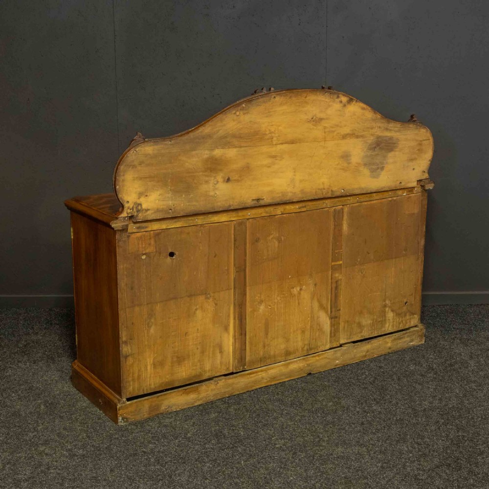 A Victorian mahogany sideboard featuring a carved backboard gallery, flame mahogany panelled doors, a central drawer, and a plinth base. View XIX