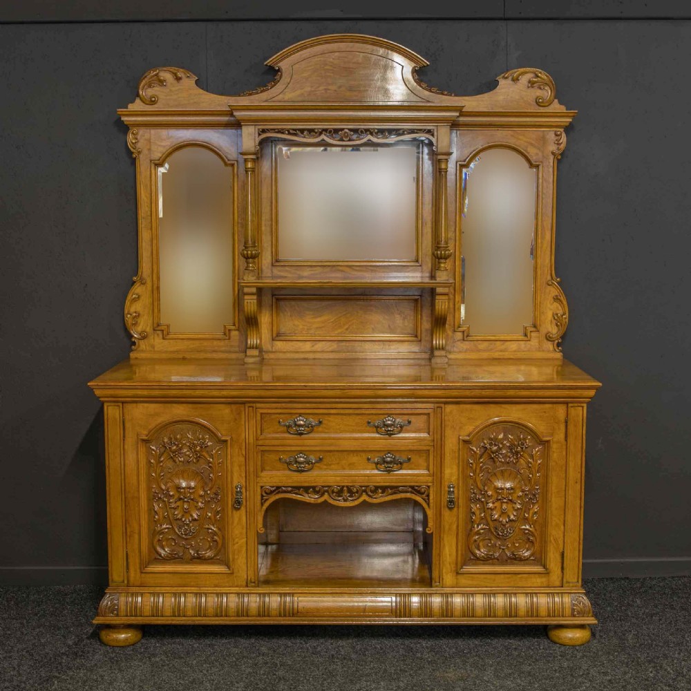Victorian pollard oak sideboard featuring a carved mirror-back superstructure, two central drawers, an open lower shelf, and flanking relief-carved cupboard doors. View V