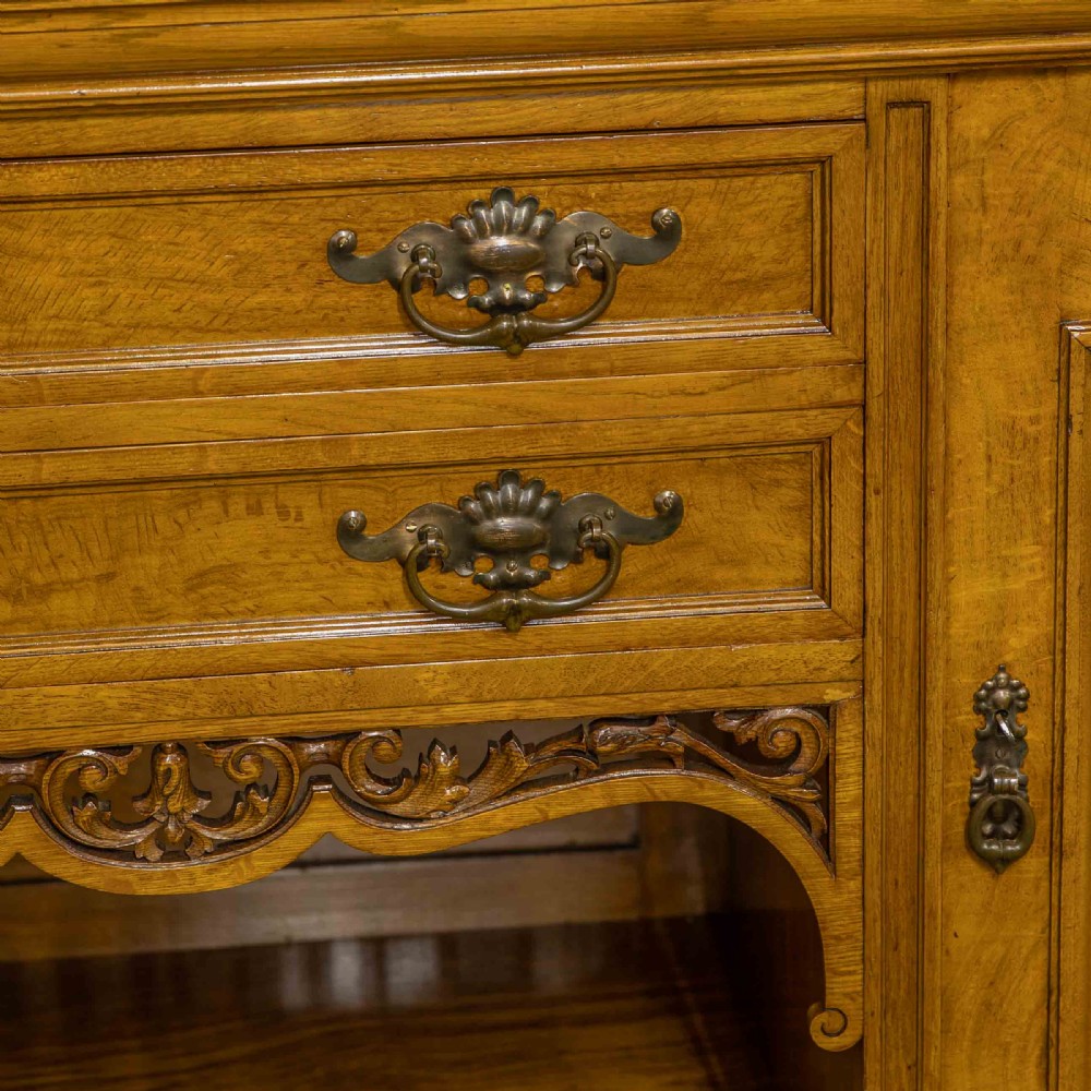 Victorian pollard oak sideboard featuring a carved mirror-back superstructure, two central drawers, an open lower shelf, and flanking relief-carved cupboard doors. View VIII