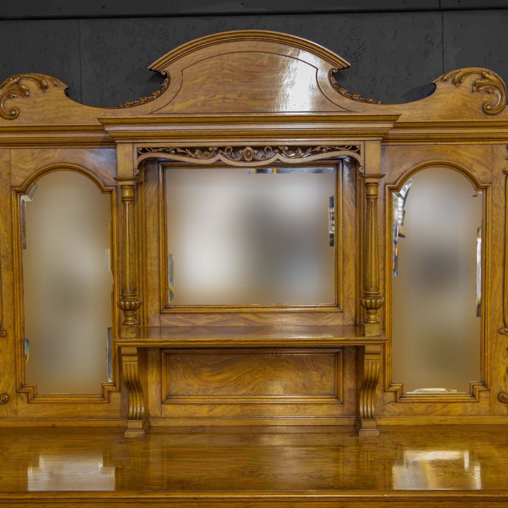 Victorian pollard oak sideboard featuring a carved mirror-back superstructure, two central drawers, an open lower shelf, and flanking relief-carved cupboard doors. View IX