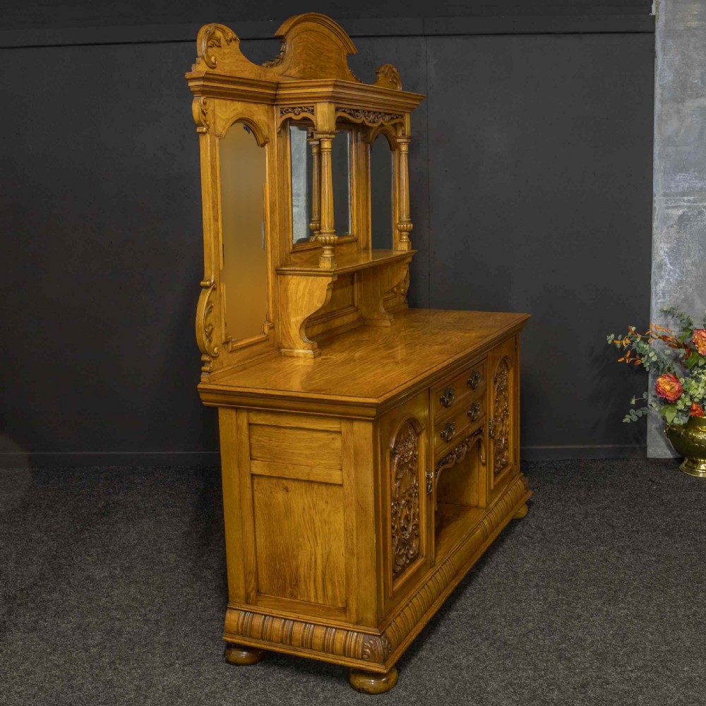 Victorian pollard oak sideboard featuring a carved mirror-back superstructure, two central drawers, an open lower shelf, and flanking relief-carved cupboard doors. View XI