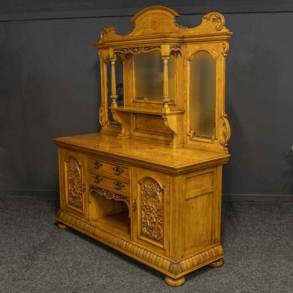 Victorian pollard oak sideboard featuring a carved mirror-back superstructure, two central drawers, an open lower shelf, and flanking relief-carved cupboard doors. View XII