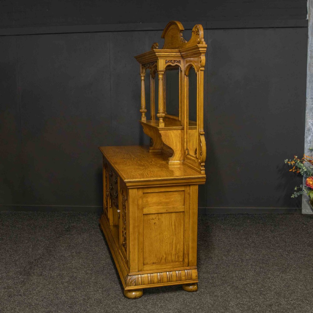 Victorian pollard oak sideboard featuring a carved mirror-back superstructure, two central drawers, an open lower shelf, and flanking relief-carved cupboard doors. View XIII
