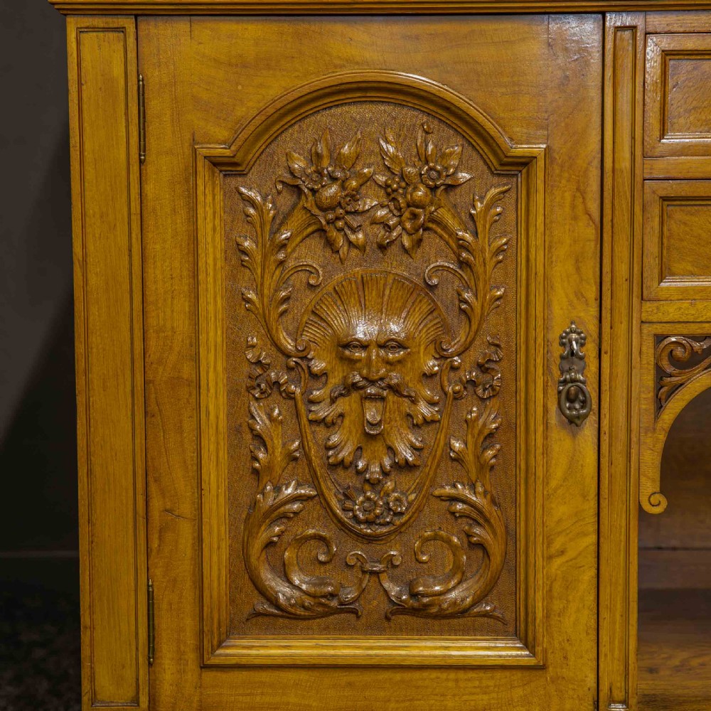 Victorian pollard oak sideboard featuring a carved mirror-back superstructure, two central drawers, an open lower shelf, and flanking relief-carved cupboard doors. View XVII