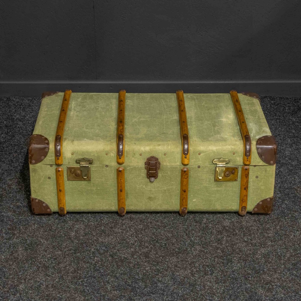 An olive green canvas-covered steamer trunk featuring wooden bentwood slats, leather corner protectors, leather side handles, and stencilled black lettering. View II