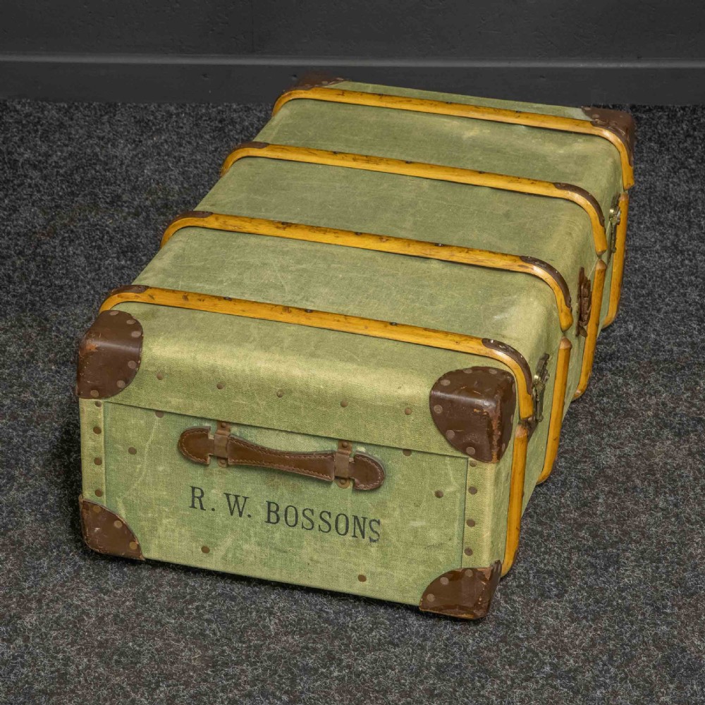 An olive green canvas-covered steamer trunk featuring wooden bentwood slats, leather corner protectors, leather side handles, and stencilled black lettering. View VII