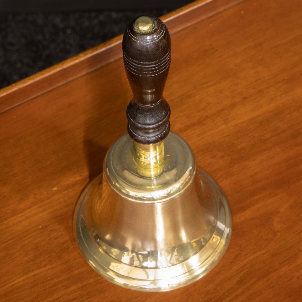 A Victorian brass handbell featuring a polished flare-mouthed bell and a dark turned wood handle with ribbed detailing. View II