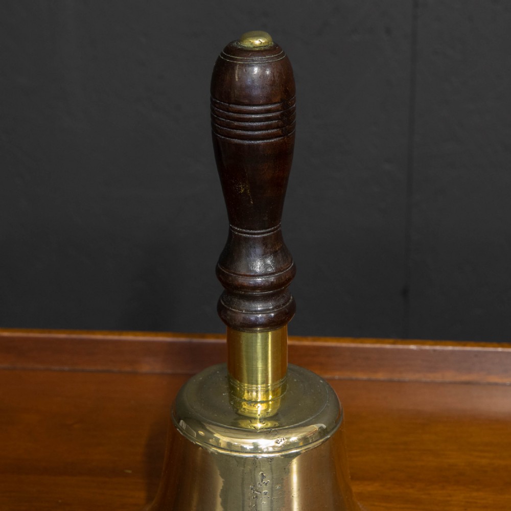 A Victorian brass handbell featuring a polished flare-mouthed bell and a dark turned wood handle with ribbed detailing. View III