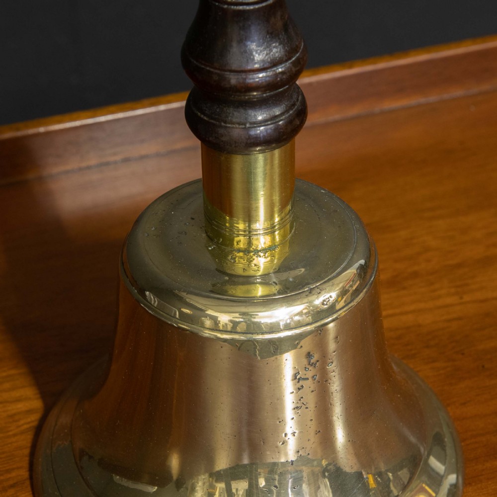 A Victorian brass handbell featuring a polished flare-mouthed bell and a dark turned wood handle with ribbed detailing. View IV