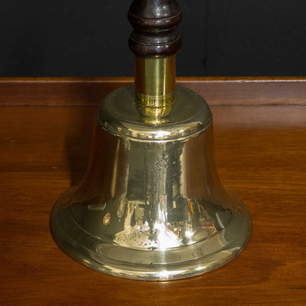 A Victorian brass handbell featuring a polished flare-mouthed bell and a dark turned wood handle with ribbed detailing. View V