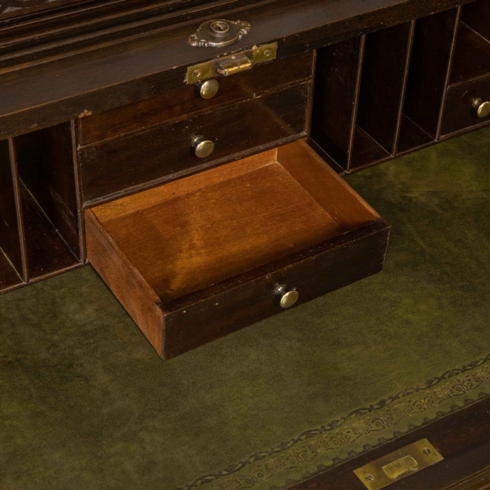 An early 20th-century Chippendale style dark mahogany roll-top desk featuring a green leather writing surface, fitted interior pigeonholes, twin drawer pedestals, and brass drop handles. View XI