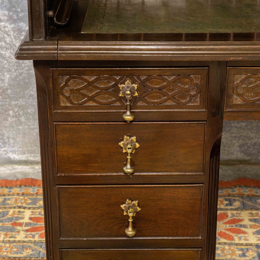 An early 20th-century Chippendale style dark mahogany roll-top desk featuring a green leather writing surface, fitted interior pigeonholes, twin drawer pedestals, and brass drop handles. View XIII