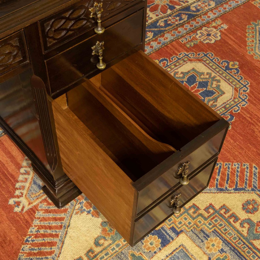 An early 20th-century Chippendale style dark mahogany roll-top desk featuring a green leather writing surface, fitted interior pigeonholes, twin drawer pedestals, and brass drop handles. View XIV