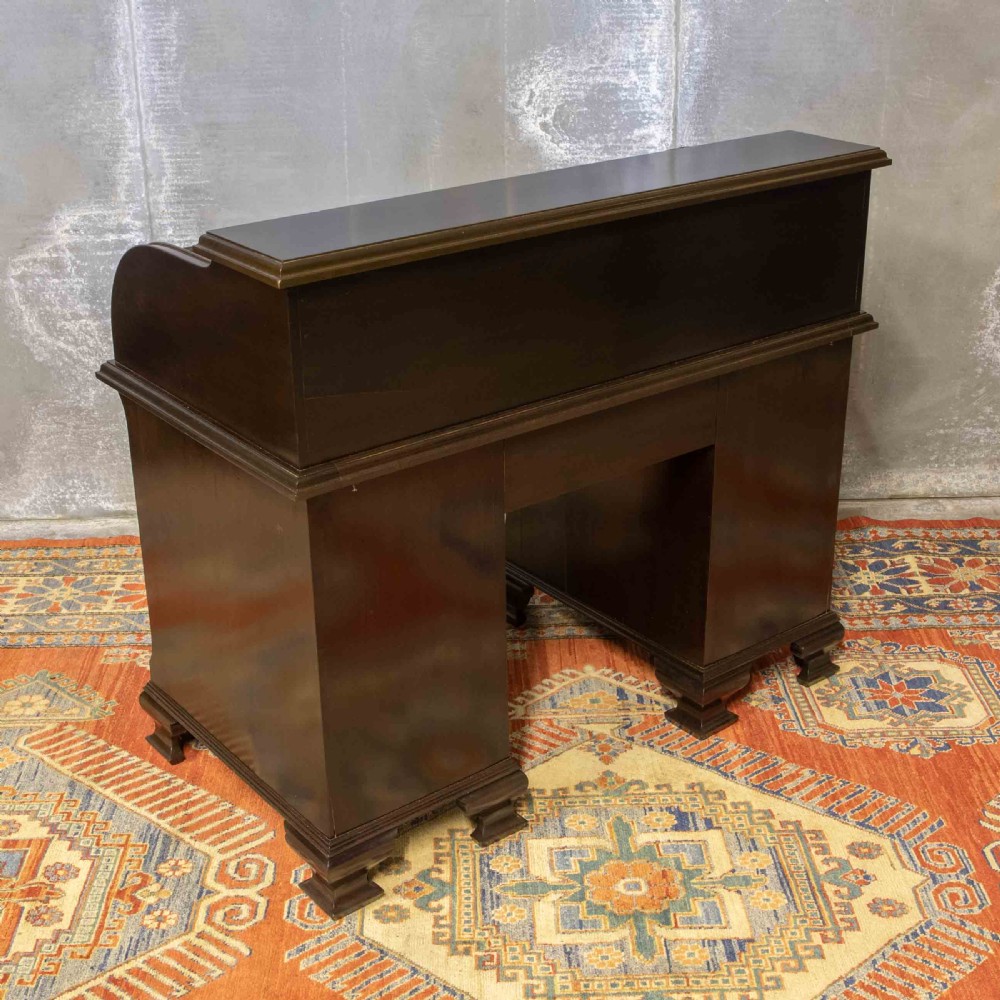 An early 20th-century Chippendale style dark mahogany roll-top desk featuring a green leather writing surface, fitted interior pigeonholes, twin drawer pedestals, and brass drop handles. View XVIII