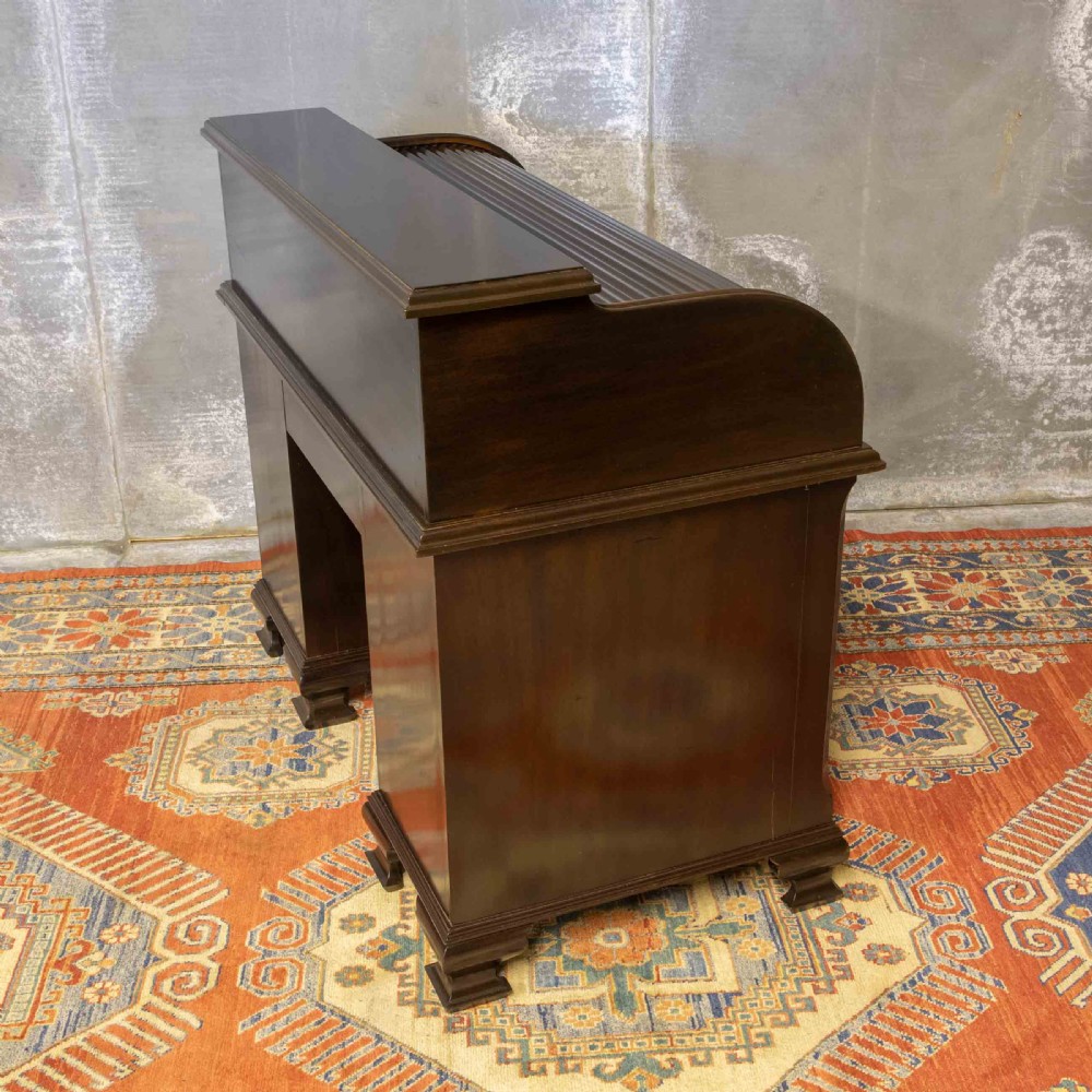 An early 20th-century Chippendale style dark mahogany roll-top desk featuring a green leather writing surface, fitted interior pigeonholes, twin drawer pedestals, and brass drop handles. View XX