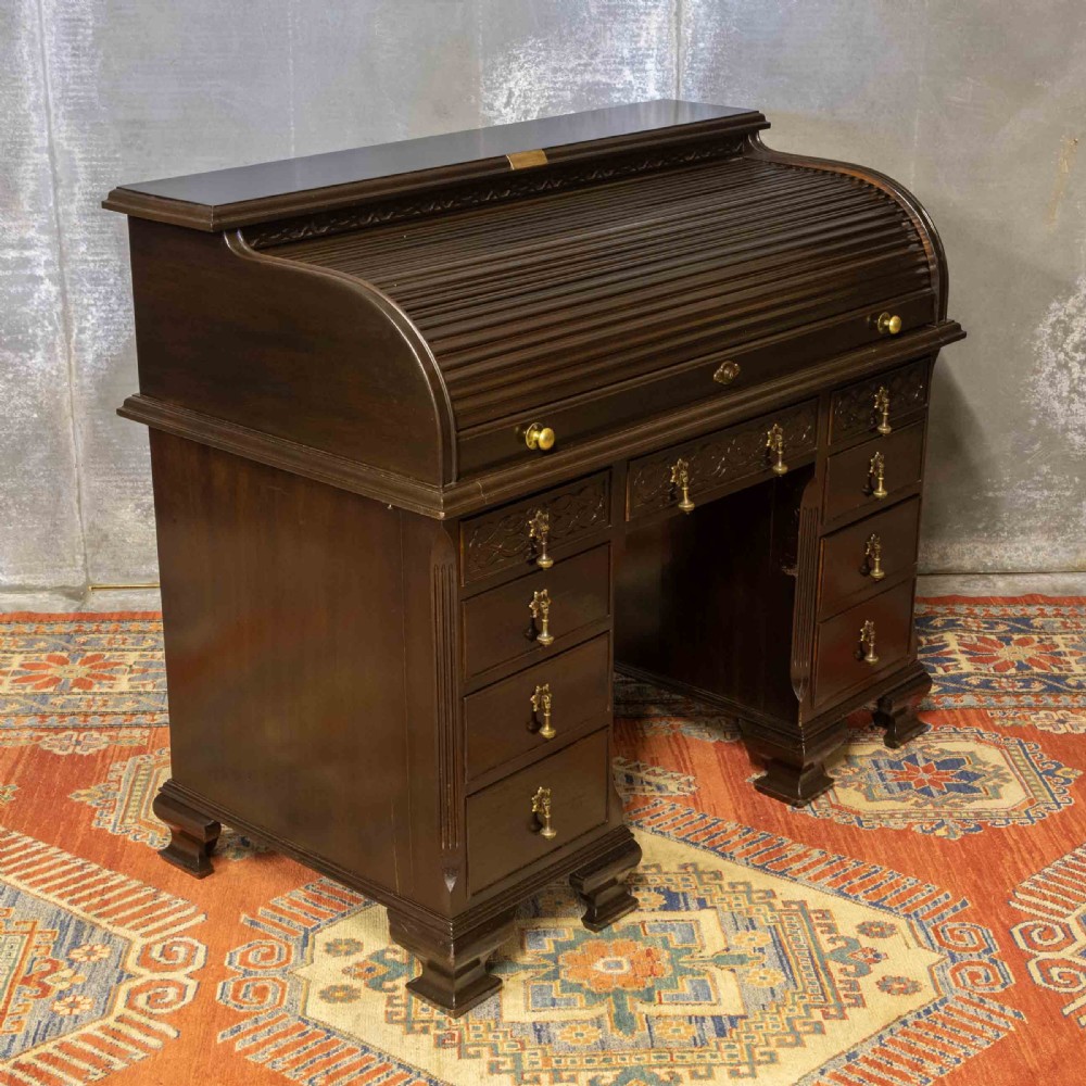 An early 20th-century Chippendale style dark mahogany roll-top desk featuring a green leather writing surface, fitted interior pigeonholes, twin drawer pedestals, and brass drop handles. View XXI