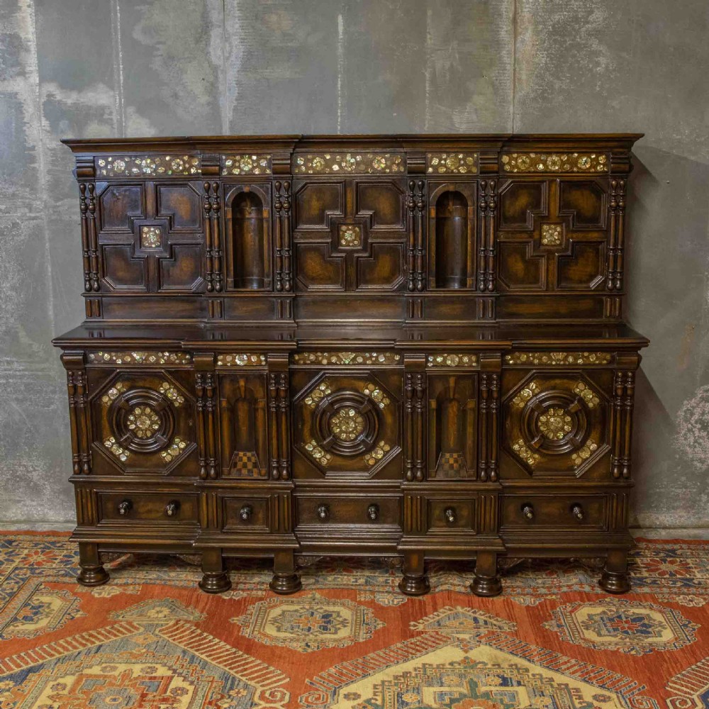 A dark oak Jacobean dresser featuring geometric mouldings, mother-of-pearl inlays, arched panels, turned split spindles, and lower drawers.