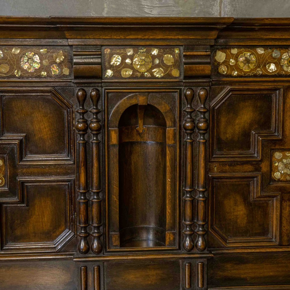 A dark oak Jacobean dresser featuring geometric mouldings, mother-of-pearl inlays, arched panels, turned split spindles, and lower drawers. View II