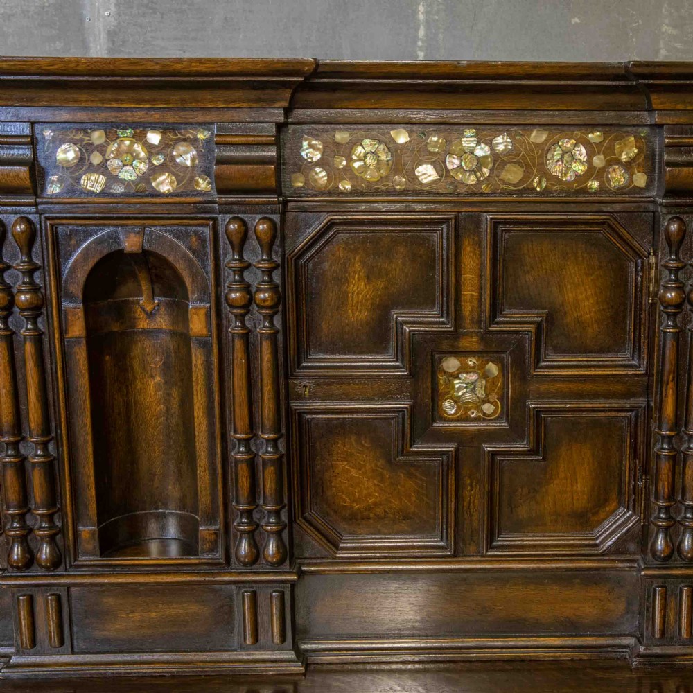 A dark oak Jacobean dresser featuring geometric mouldings, mother-of-pearl inlays, arched panels, turned split spindles, and lower drawers. View IV