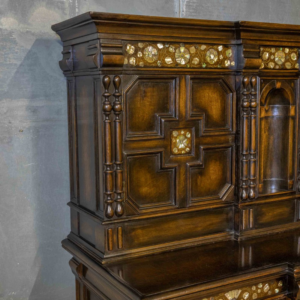 A dark oak Jacobean dresser featuring geometric mouldings, mother-of-pearl inlays, arched panels, turned split spindles, and lower drawers. View V