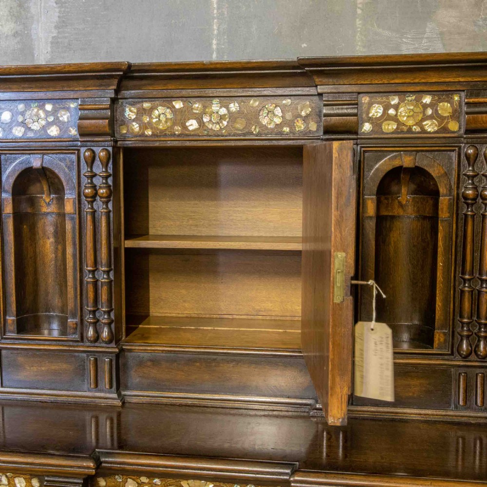 A dark oak Jacobean dresser featuring geometric mouldings, mother-of-pearl inlays, arched panels, turned split spindles, and lower drawers. View VI