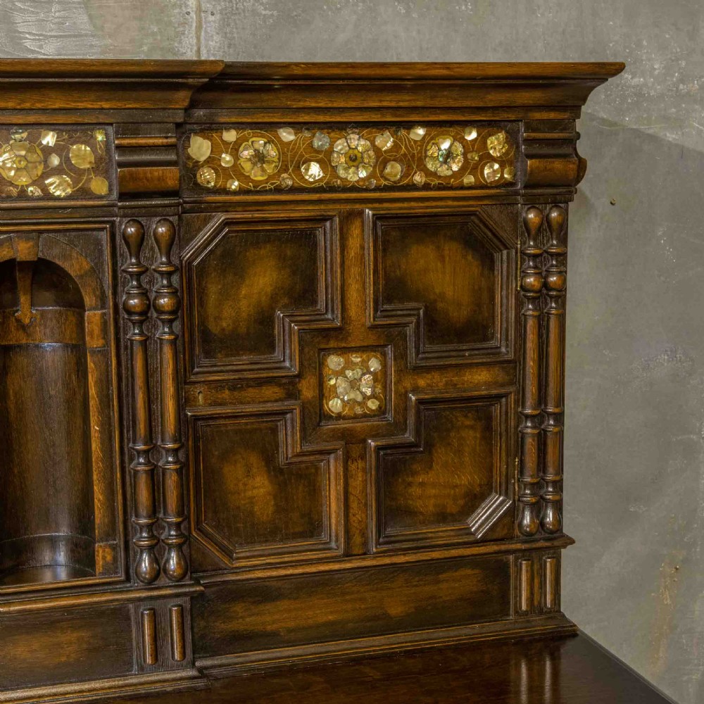 A dark oak Jacobean dresser featuring geometric mouldings, mother-of-pearl inlays, arched panels, turned split spindles, and lower drawers. View VII