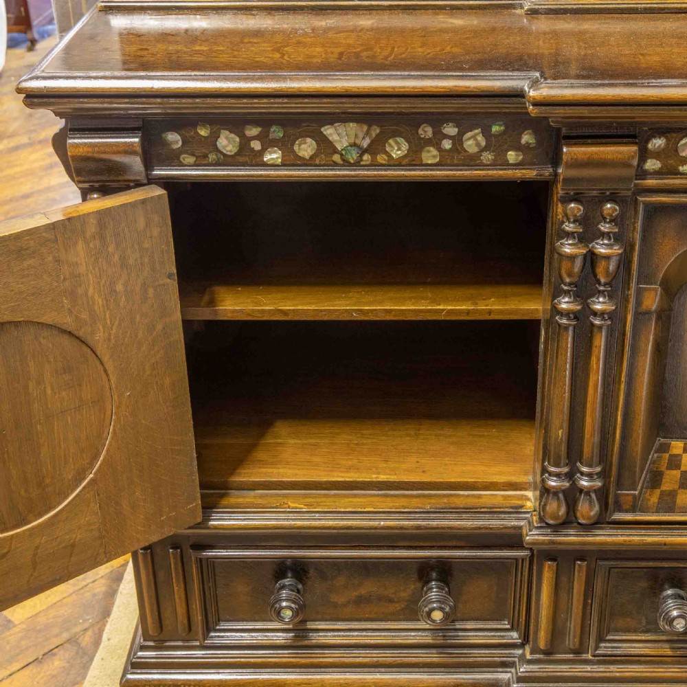 A dark oak Jacobean dresser featuring geometric mouldings, mother-of-pearl inlays, arched panels, turned split spindles, and lower drawers. View XII