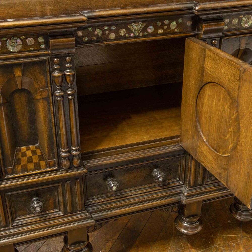 A dark oak Jacobean dresser featuring geometric mouldings, mother-of-pearl inlays, arched panels, turned split spindles, and lower drawers. View XIV