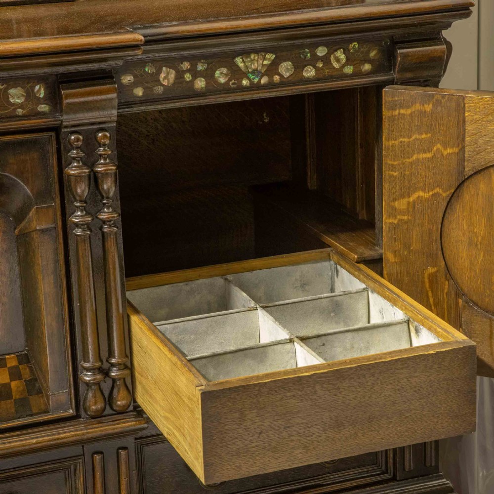 A dark oak Jacobean dresser featuring geometric mouldings, mother-of-pearl inlays, arched panels, turned split spindles, and lower drawers. View XV
