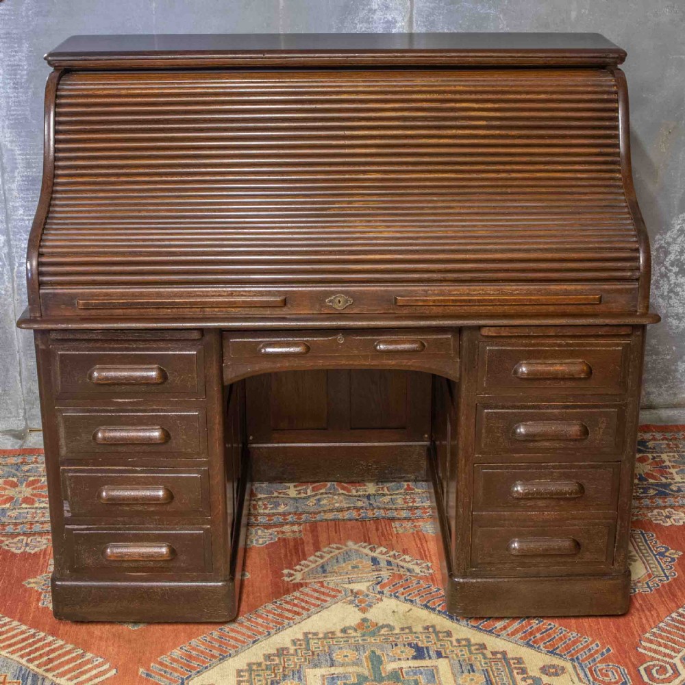 A late Victorian oak roll-top desk with an open tambour shutter revealing internal pigeonholes above a twin-pedestal base with wooden handles. View IX
