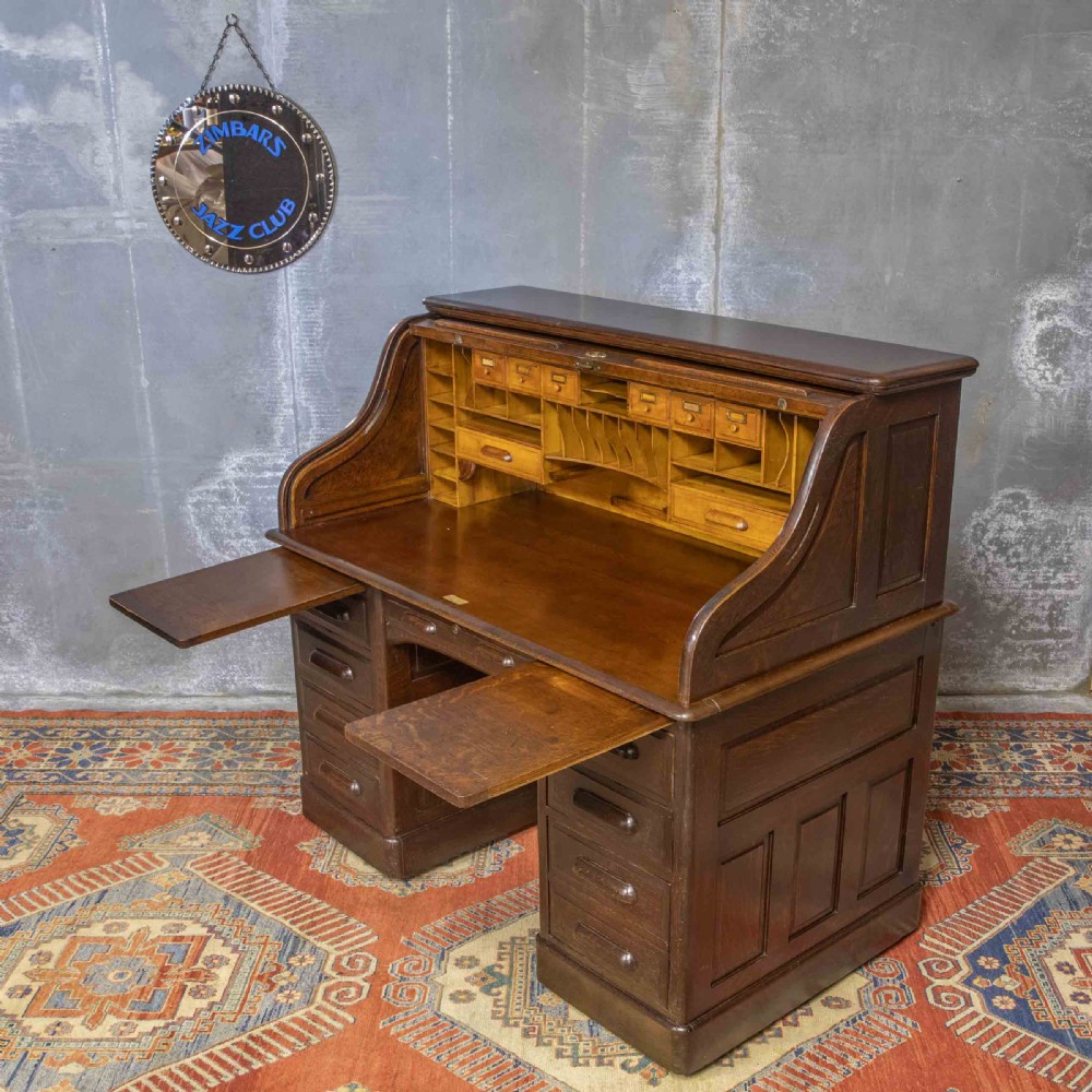 A late Victorian oak roll-top desk with an open tambour shutter revealing internal pigeonholes above a twin-pedestal base with wooden handles. View XI