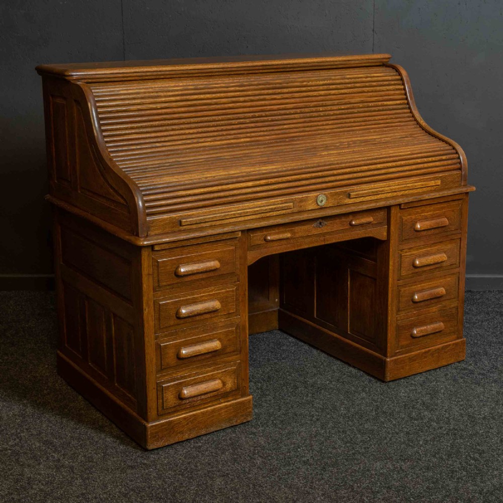 An Edwardian oak roll top desk with a raised slatted tambour front revealing fitted interior compartments above twin pedestal drawers. View VII