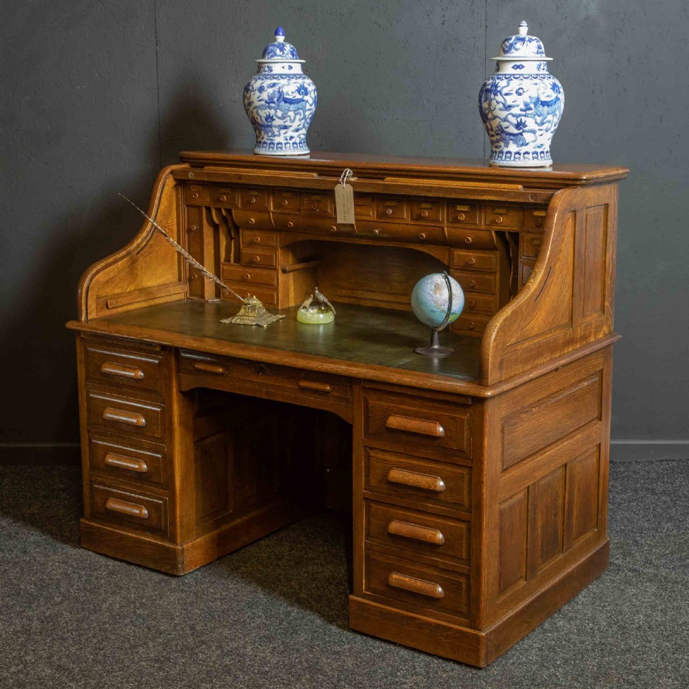 An Edwardian oak roll top desk with a raised slatted tambour front revealing fitted interior compartments above twin pedestal drawers. View VIII