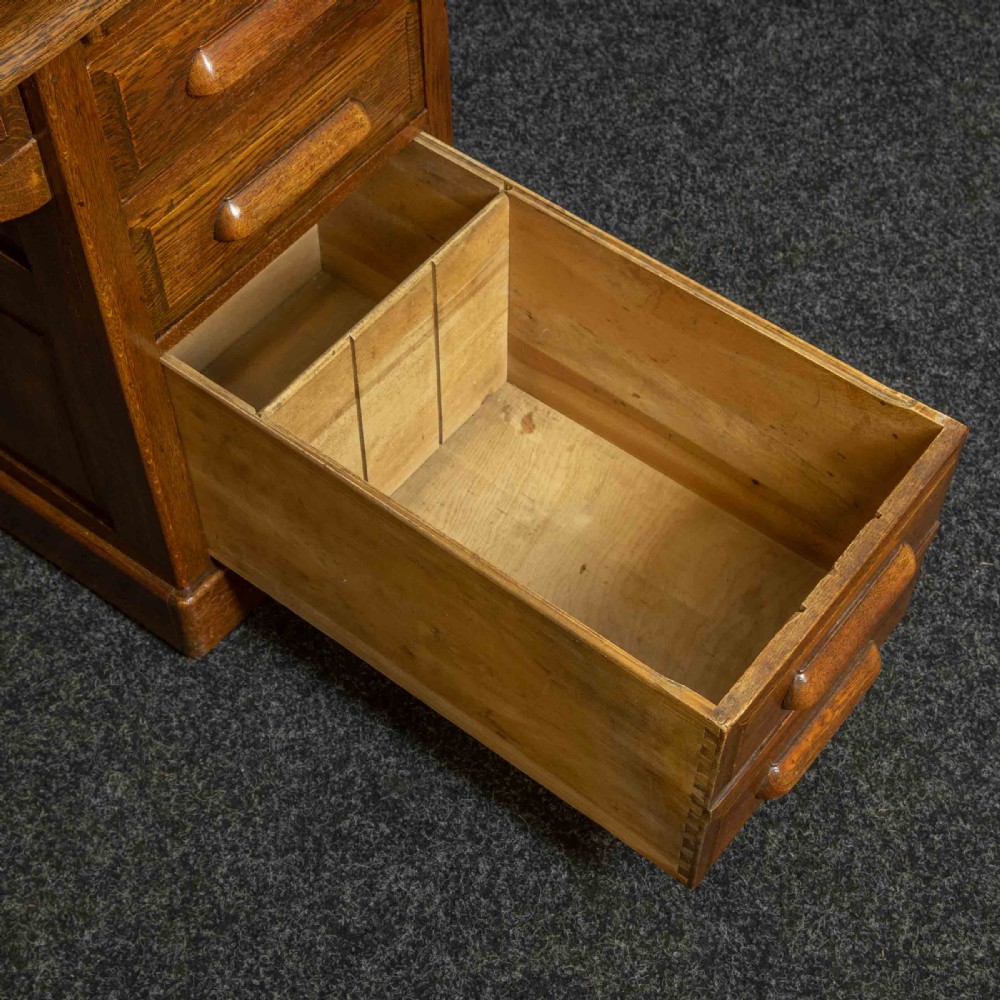 An Edwardian oak roll top desk with a raised slatted tambour front revealing fitted interior compartments above twin pedestal drawers. View X