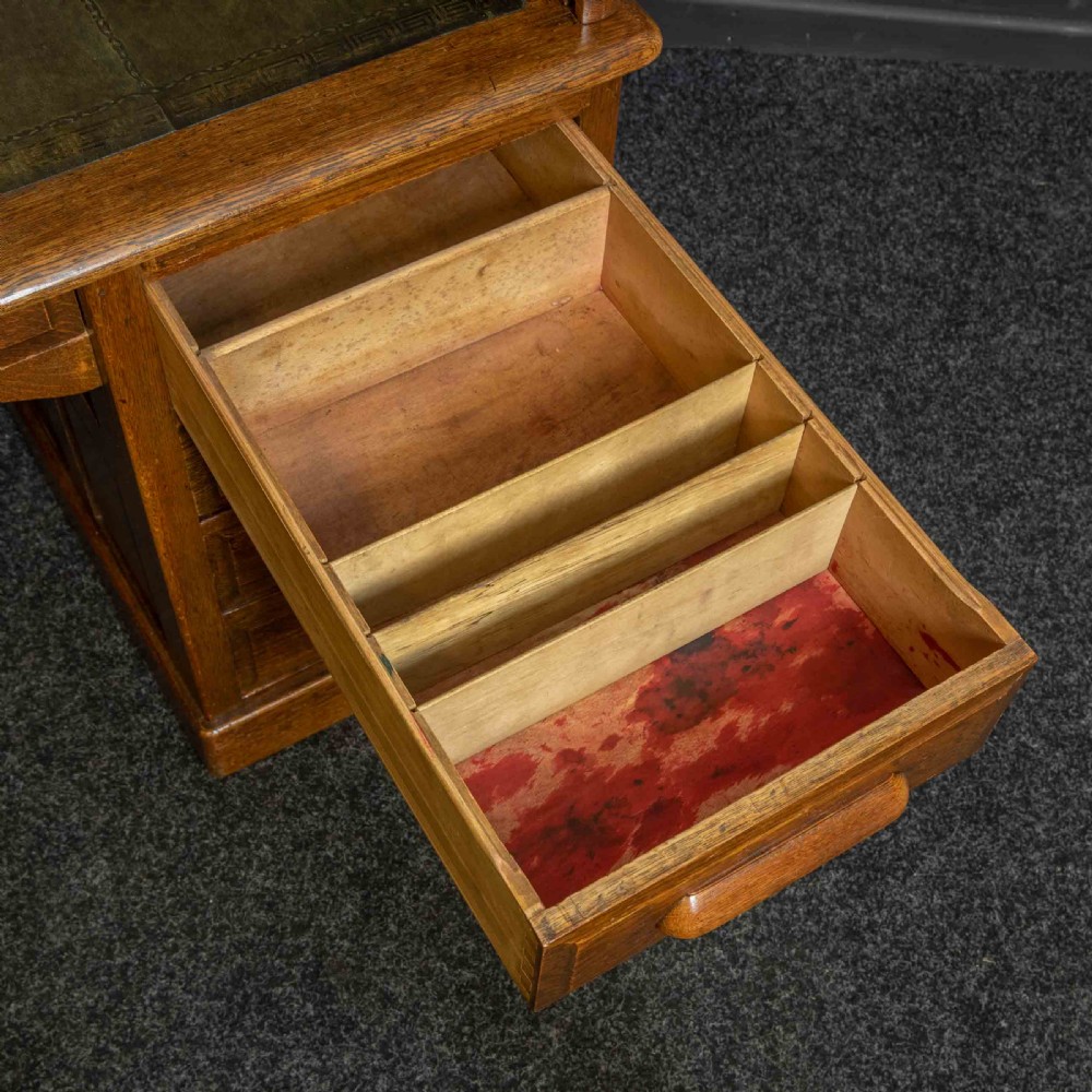 An Edwardian oak roll top desk with a raised slatted tambour front revealing fitted interior compartments above twin pedestal drawers. View XI