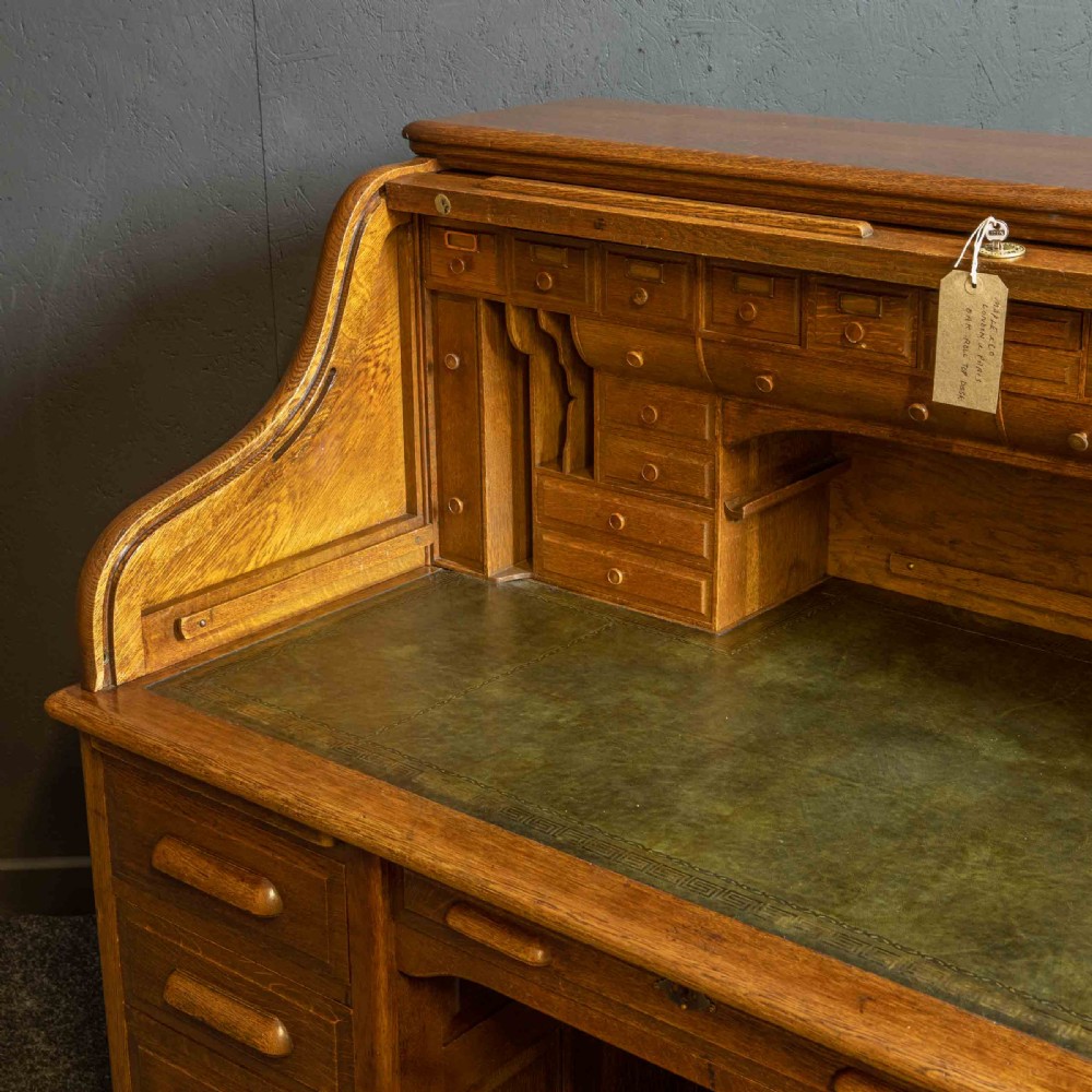 An Edwardian oak roll top desk with a raised slatted tambour front revealing fitted interior compartments above twin pedestal drawers. View XIII