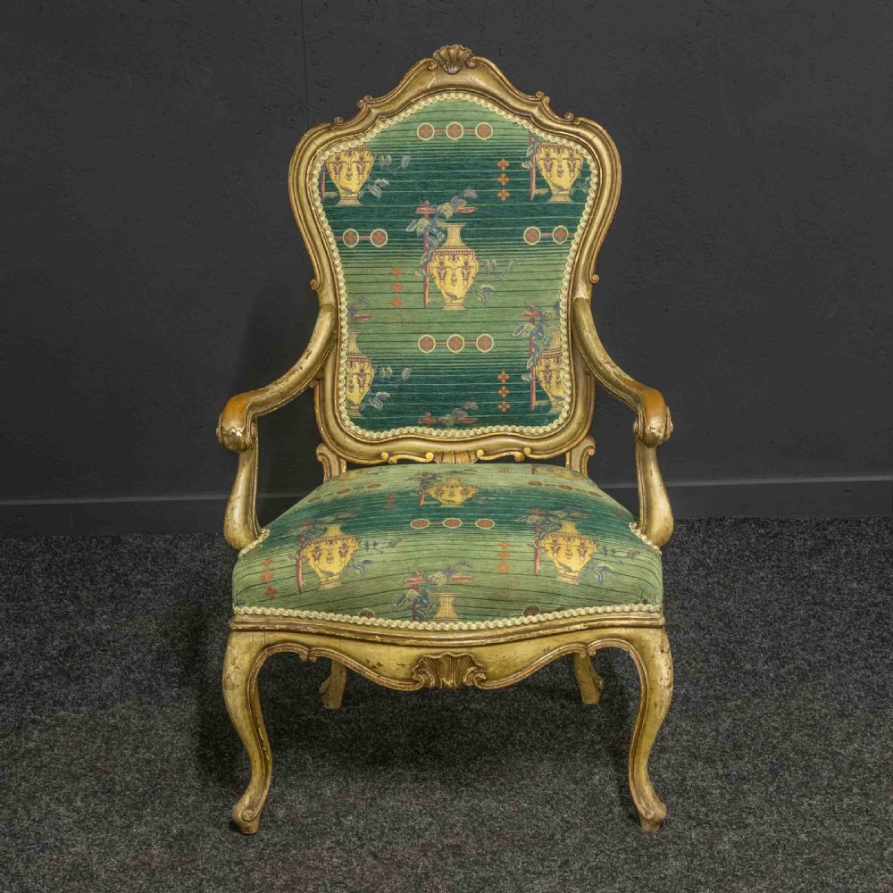 A 19th-century French giltwood fauteuil open armchair featuring carved shell motifs, cabriole legs, and patterned green upholstery.
