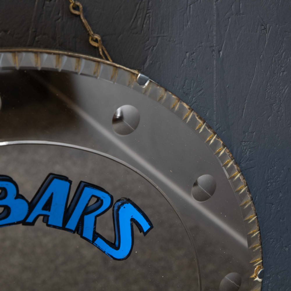 A circular frameless wall mirror featuring blue typography that reads Zimbars Jazz Club, suspended by a top chain. View IV