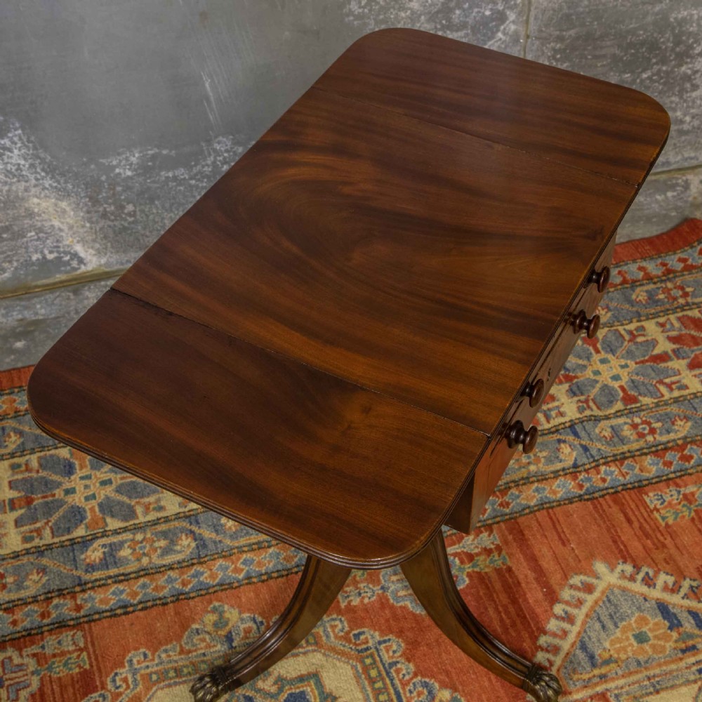 A Regency mahogany drop-leaf worktable featuring two drawers with wooden knobs, a turned pedestal column, and tripod legs with brass paw feet. View III