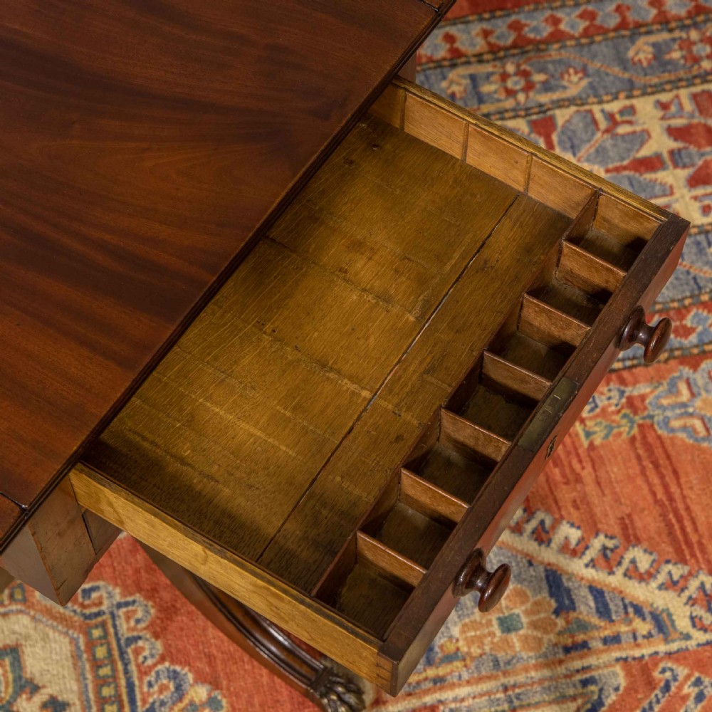 A Regency mahogany drop-leaf worktable featuring two drawers with wooden knobs, a turned pedestal column, and tripod legs with brass paw feet. View VI