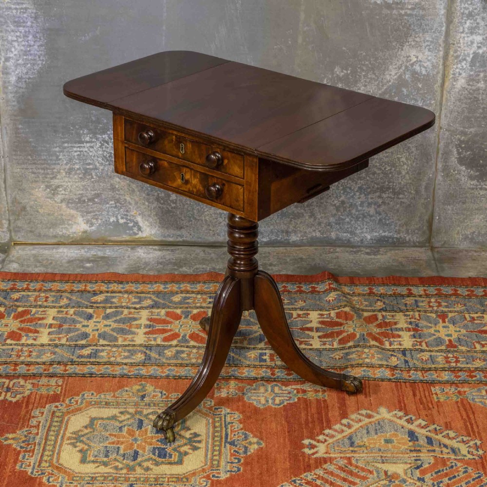 A Regency mahogany drop-leaf worktable featuring two drawers with wooden knobs, a turned pedestal column, and tripod legs with brass paw feet. View X