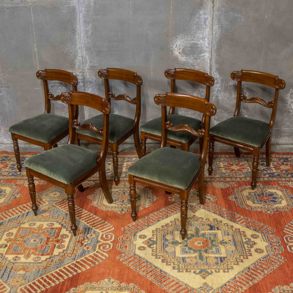 A set of six William IV mahogany dining chairs featuring carved top rails, turned front legs, and green velvet upholstered seats. View II