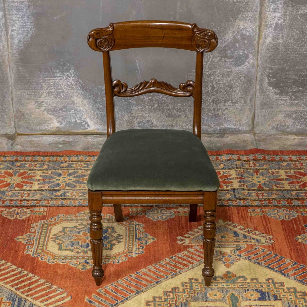 A set of six William IV mahogany dining chairs featuring carved top rails, turned front legs, and green velvet upholstered seats. View IV