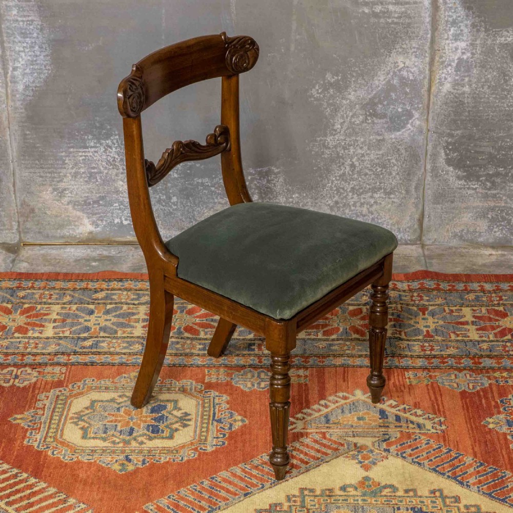 A set of six William IV mahogany dining chairs featuring carved top rails, turned front legs, and green velvet upholstered seats. View V