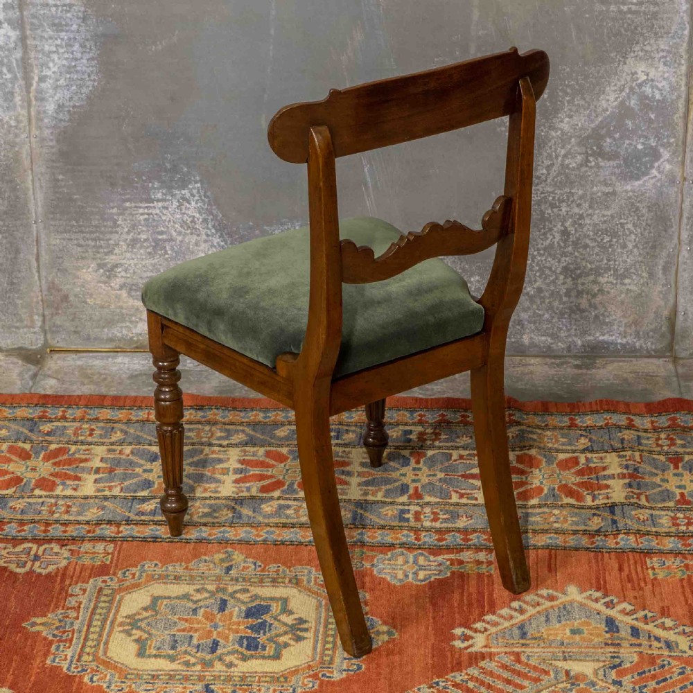 A set of six William IV mahogany dining chairs featuring carved top rails, turned front legs, and green velvet upholstered seats. View VI
